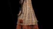 A double faced, tall woven dance mask from Kanganaman Village. The mask has two hand holes, a raffia skirt, and two holes in the lower face for the dancer to see out. Side View.